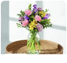 The Anna bouquet of pink, purple and yellow flowers in a glass vase