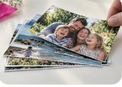 A hand holding a small stack of glossy 6x4 family photo prints