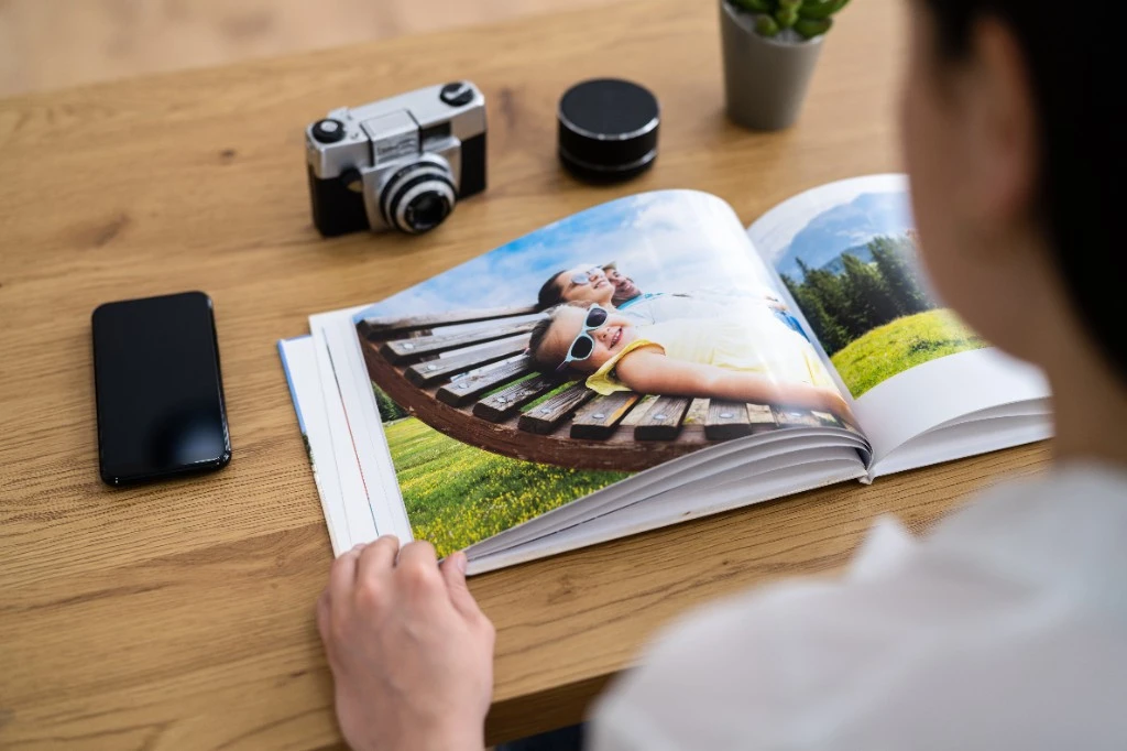 Personalised photo book open on a table next to a camera and a coffee