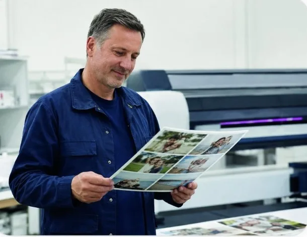 FreeSnaps print technician checking a sheet of family photo prints before they are packed for Amazon Shipping delivery